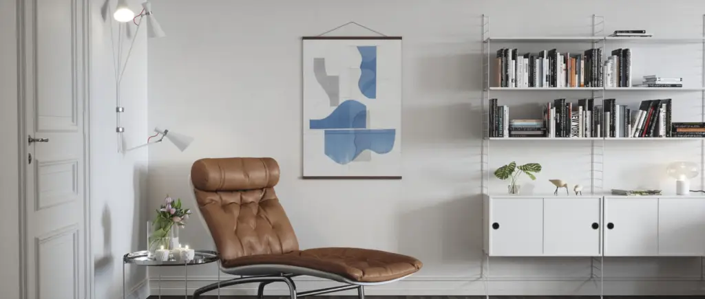 image Modern living room with brown leather chair, abstract blue art, wall-mounted bookshelf, and minimalist decor. | Sky Rye Design Modern living room with brown leather chair, abstract blue art, wall-mounted bookshelf, and minimalist decor.