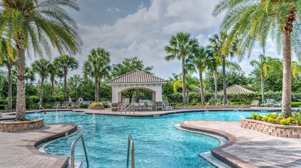 Tropical outdoor pool with palm trees, sunny skies, and a cozy cabana, perfect for relaxation and leisure.