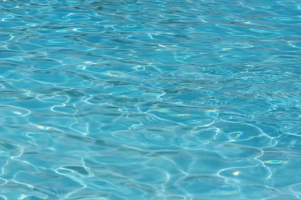 Clear blue pool water with gentle ripples under sunlight, creating a serene and refreshing aquatic view.