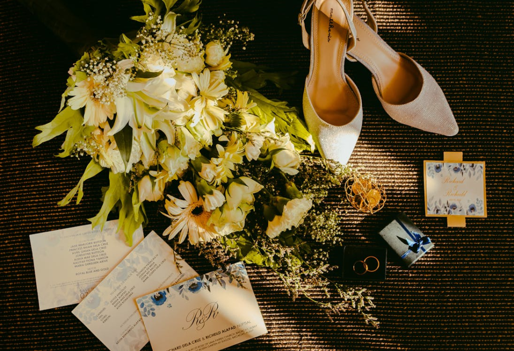 Elegant wedding flat lay with bouquet, invitations, bridal shoes, and rings.