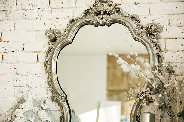 Ornate vintage mirror on white brick wall with floral decor.