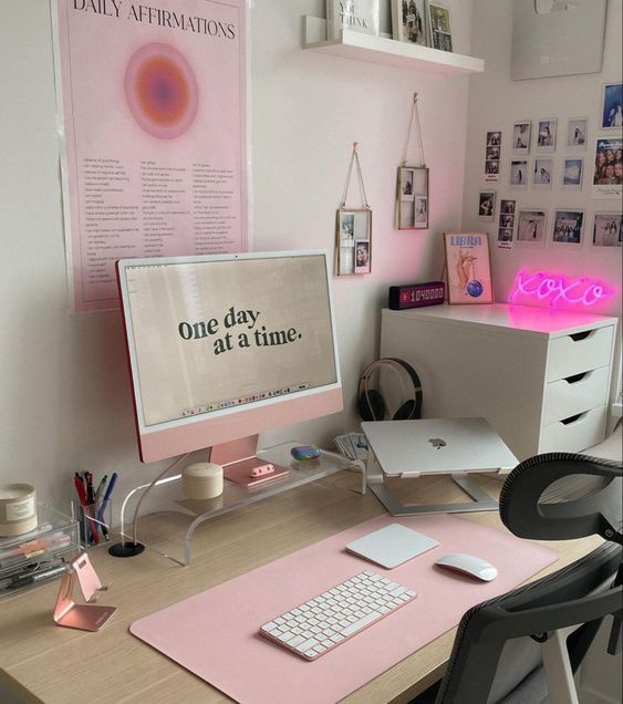 Modern desk setup with pink accents, motivational screen, and cozy decor for a productive workspace.