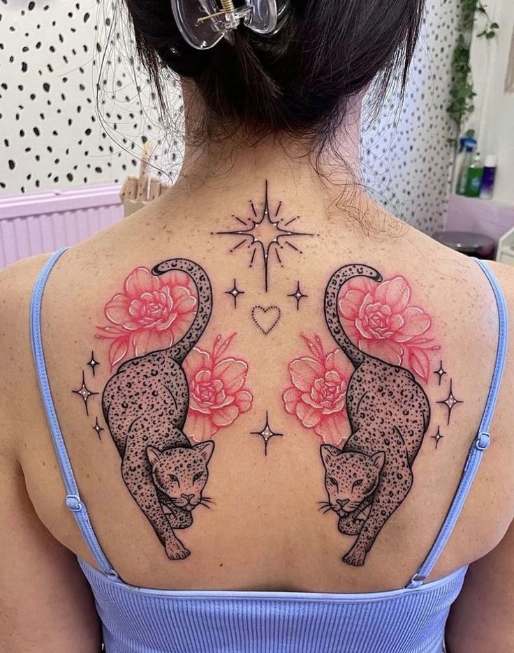 Back tattoo with mirrored leopards, pink flowers, sparkling stars, and a heart design.