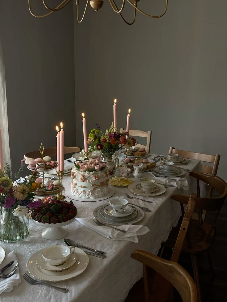 Elegant dinner table with floral cake, macarons, and candles set for a soirée.