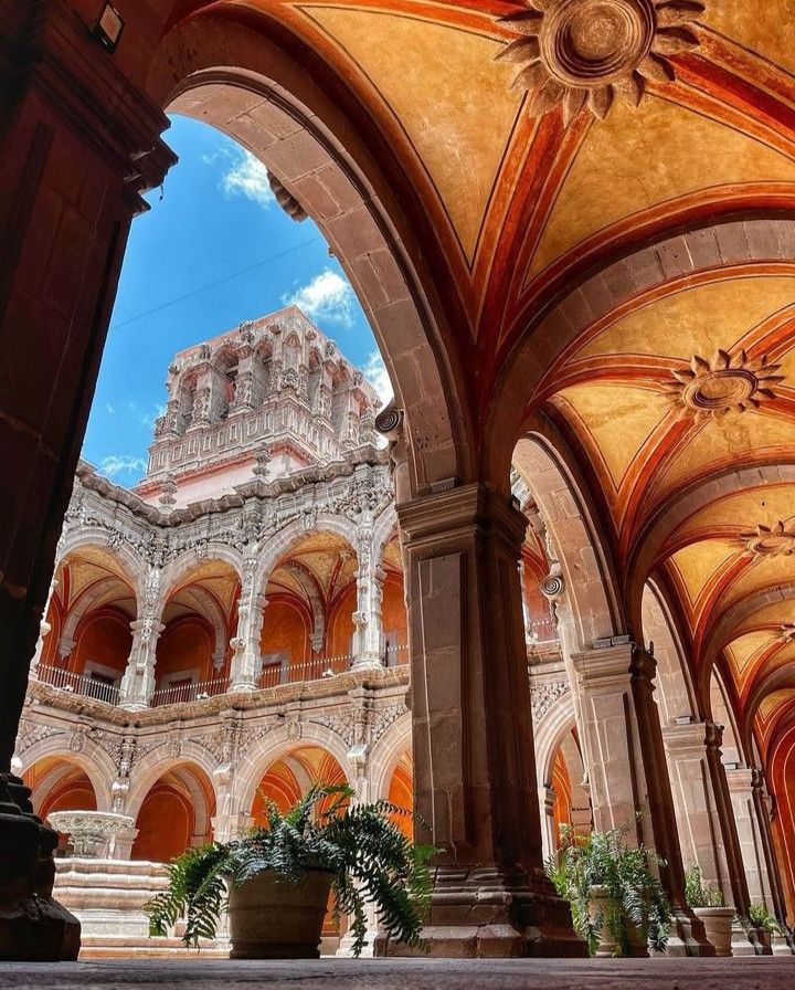 Ornate architectural arches and intricate designs in a historic courtyard under a bright blue sky.