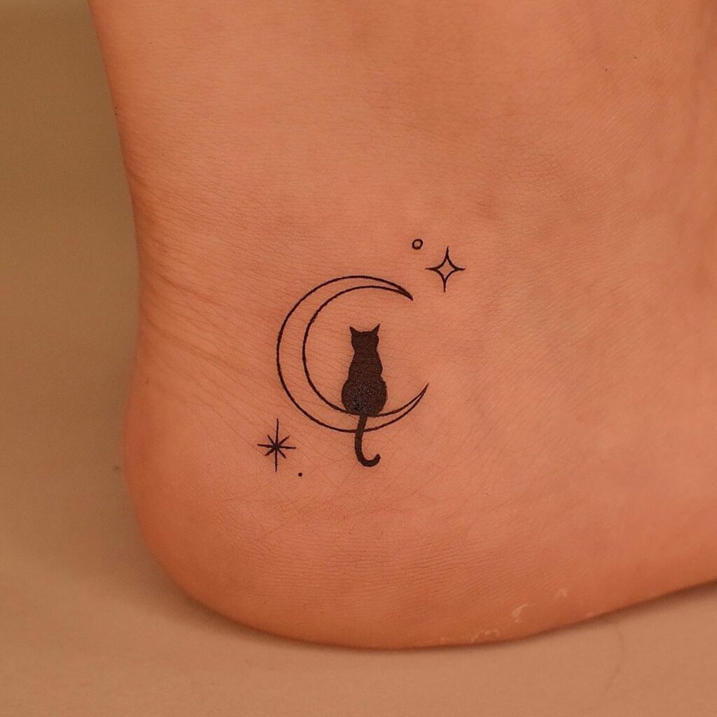 Minimalist black cat on crescent moon tattoo, ankle placement. Small stars and dots for added detail on skin.