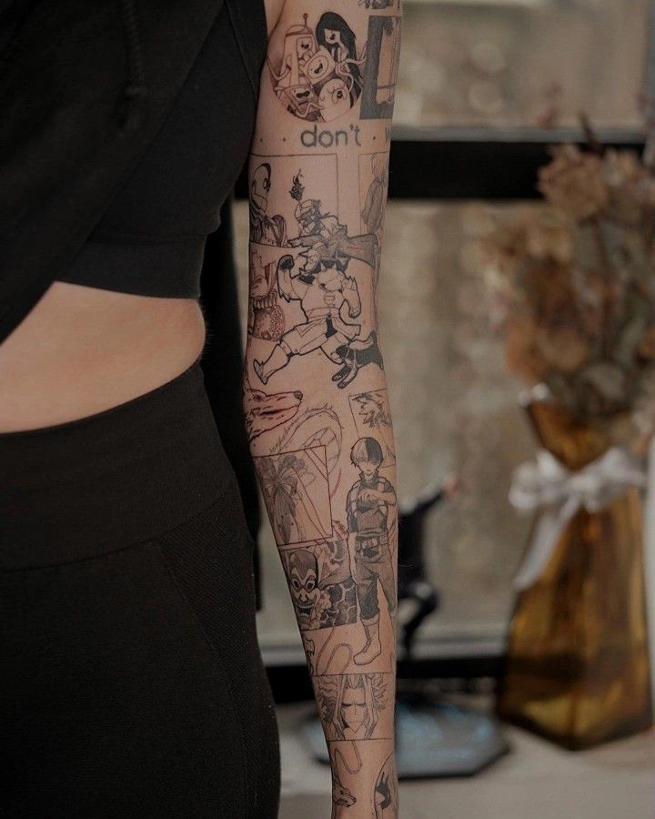 Arm with detailed black ink geek-themed tattoos featuring various characters and designs against a neutral background.