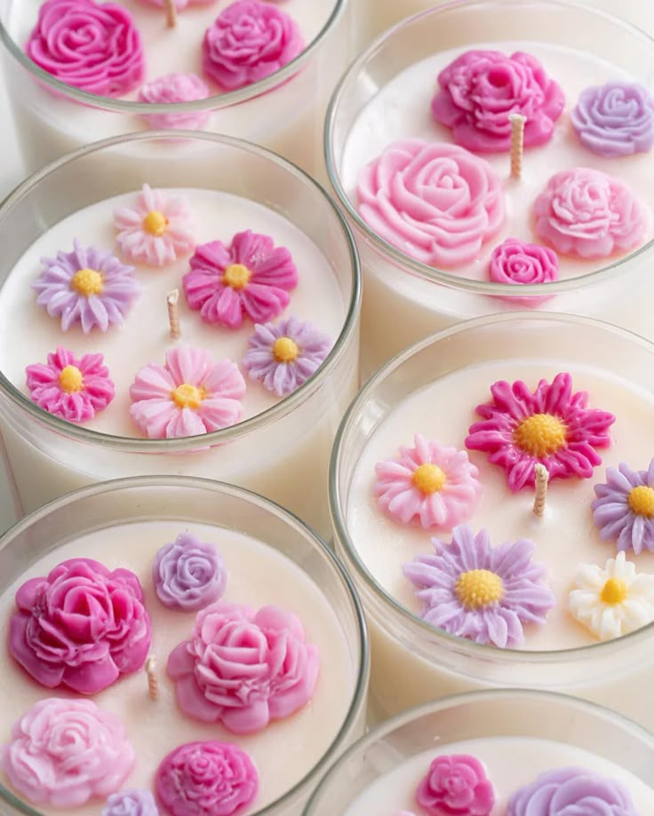 Decorative floral candles in glass jars, featuring intricate pink, purple, and yellow flower designs.