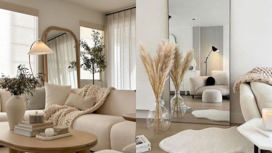 Minimalist living room with beige decor, mirrors, pampas grass, textured throw on sofa, and soft lighting.