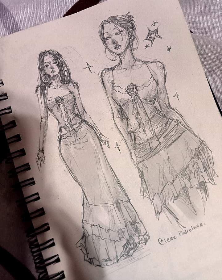 Sketch of two elegant women in long dresses with lace and floral details in a notebook, artistic fashion illustration.