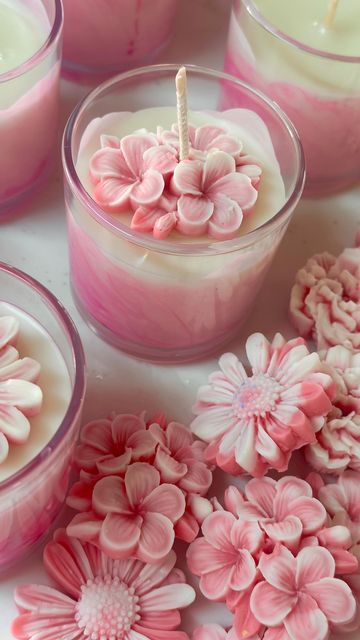 Pink floral candle in a glass jar surrounded by decorative flower accents, creating a romantic ambiance.