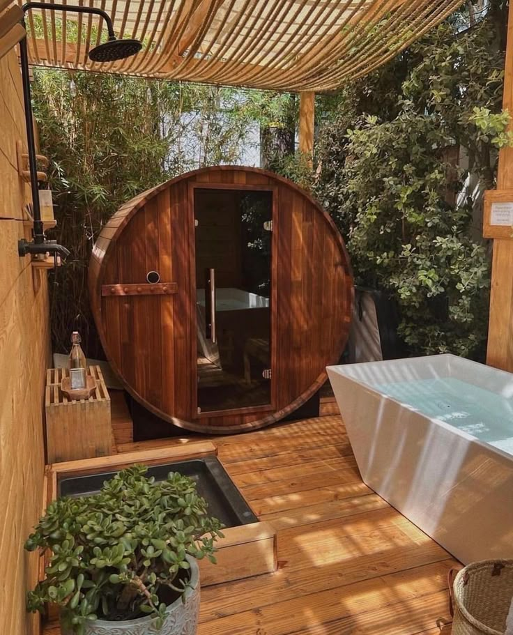 Outdoor spa with wooden barrel sauna, bathtub, and lush greenery. Perfect for relaxation and rejuvenation.