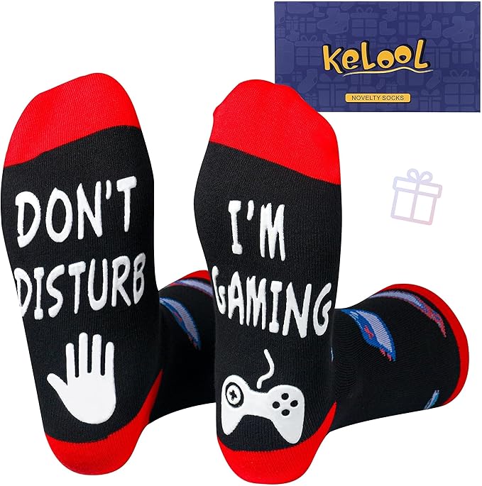 Black and red novelty socks with 'Don't Disturb, I'm Gaming' print and gaming icons, gift box in background.