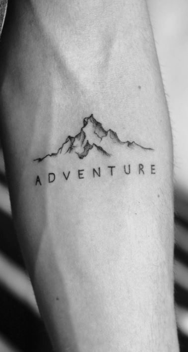 Minimalist mountain tattoo on an arm with the word Adventure in uppercase letters, symbolizing exploration and wanderlust.