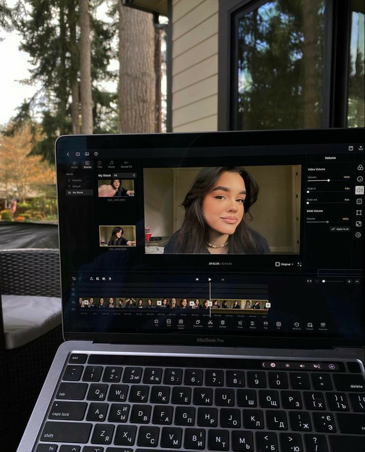 Laptop showing video editing software, displaying image of a person, outside near a house and trees in the background.