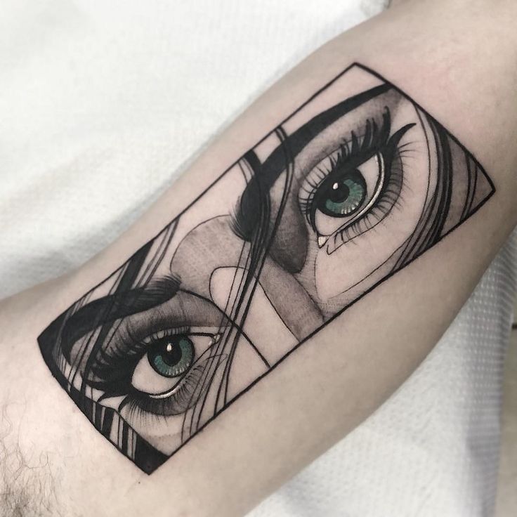 Tattoo of realistic green eyes on an arm, framed by abstract lines, showcasing detailed artistry and precision.