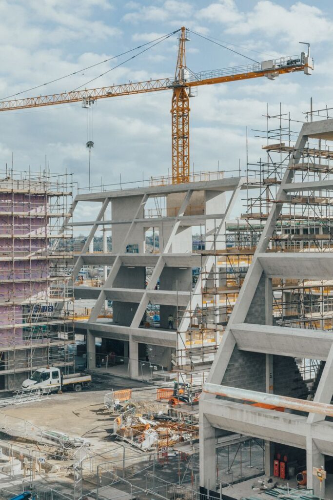 Urban construction site with cranes and scaffolding under a cloudy sky, showcasing modern building development.