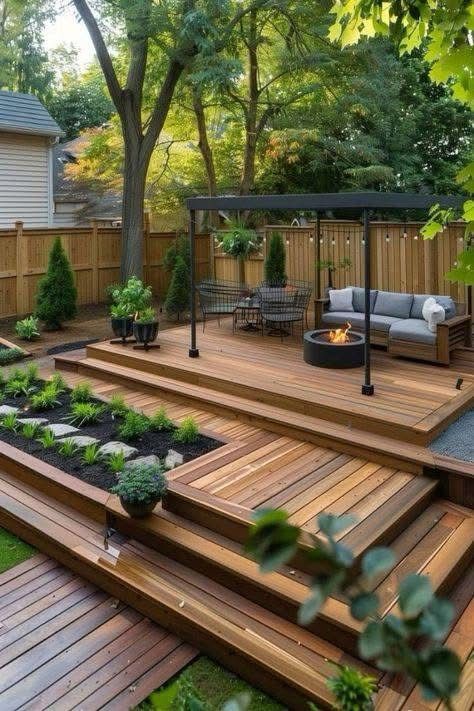 Modern backyard patio with wooden decking, cozy seating, a fire pit, and lush greenery creating a relaxing outdoor space.