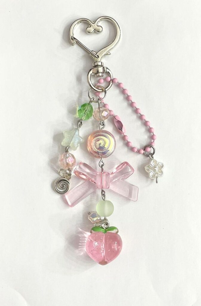 Cute pink keychain with heart clasp, featuring a bow, pastel beads, and a decorative pink peach charm.