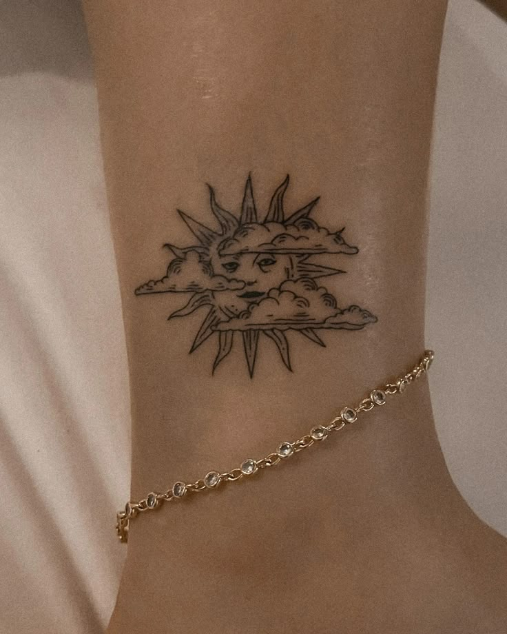 Minimal sun and cloud tattoo on ankle, adorned with a delicate gold anklet.