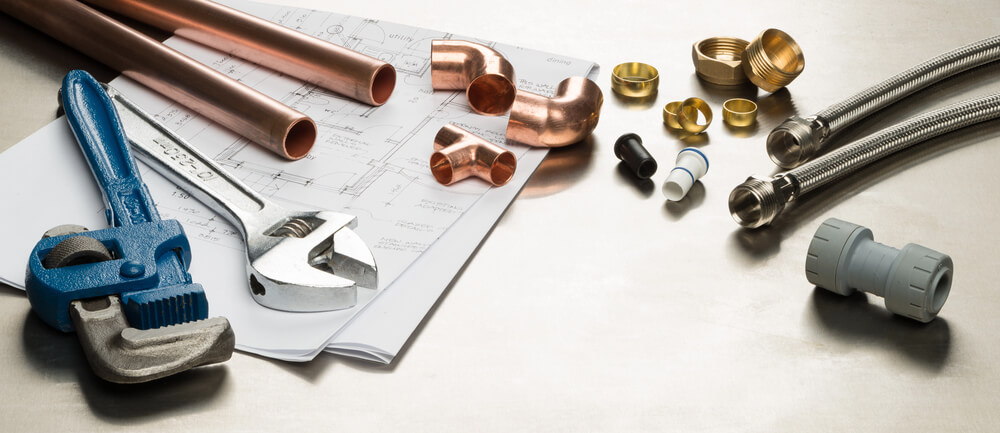 Plumbing tools and pipes on blueprint. Wrench, copper fittings, and hoses ready for home or commercial plumbing installation.