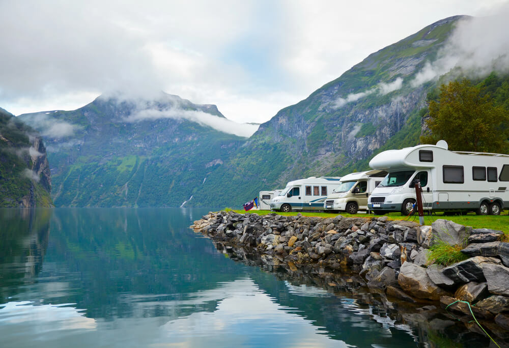 RVs parked beside a serene lake with misty mountains in the background, perfect for a peaceful camping getaway. Selling Your Mobile Home