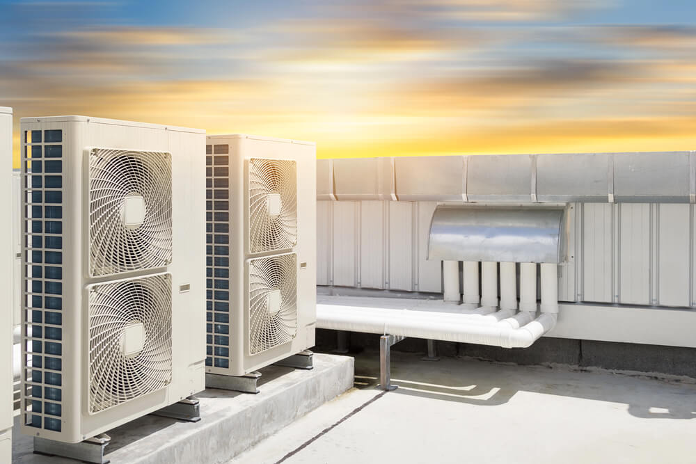 Rooftop HVAC units against a sunset sky, showcasing modern air conditioning system efficiency and design.