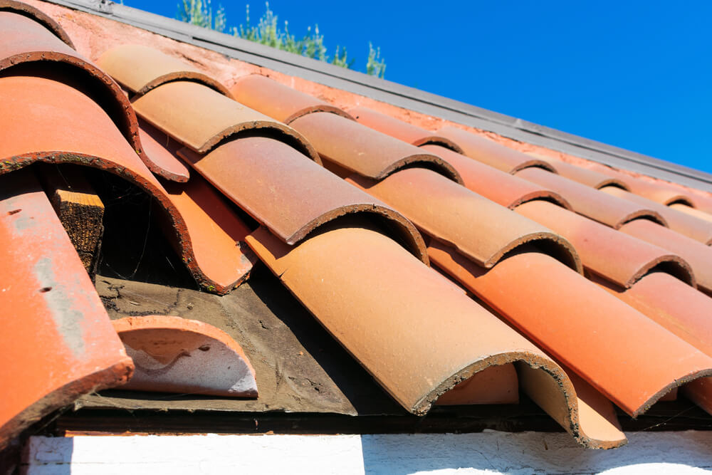 Red clay roof tiles under a clear blue sky, highlighting their curved design and vibrant color.