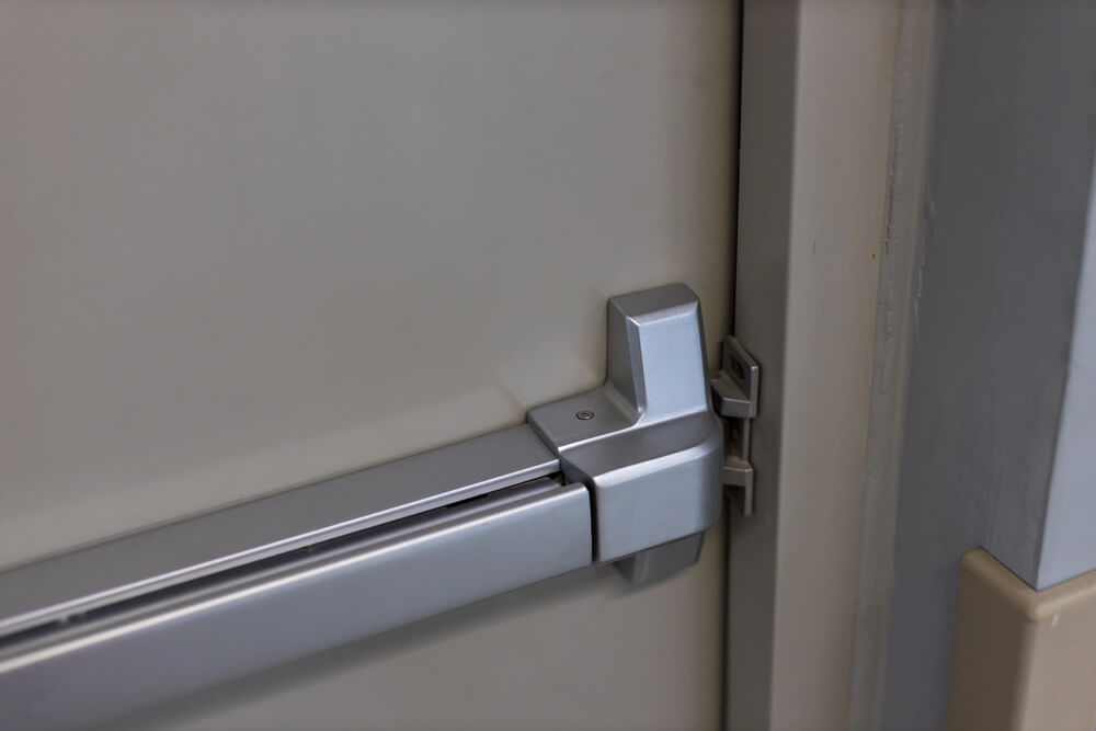 Close-up of a metal panic bar on an emergency exit door, emphasizing secure and accessible building safety features.