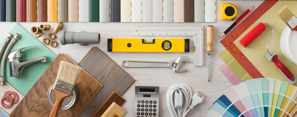 Home improvement tools and color samples on a table, including brushes, level, wrench, and paint swatches.