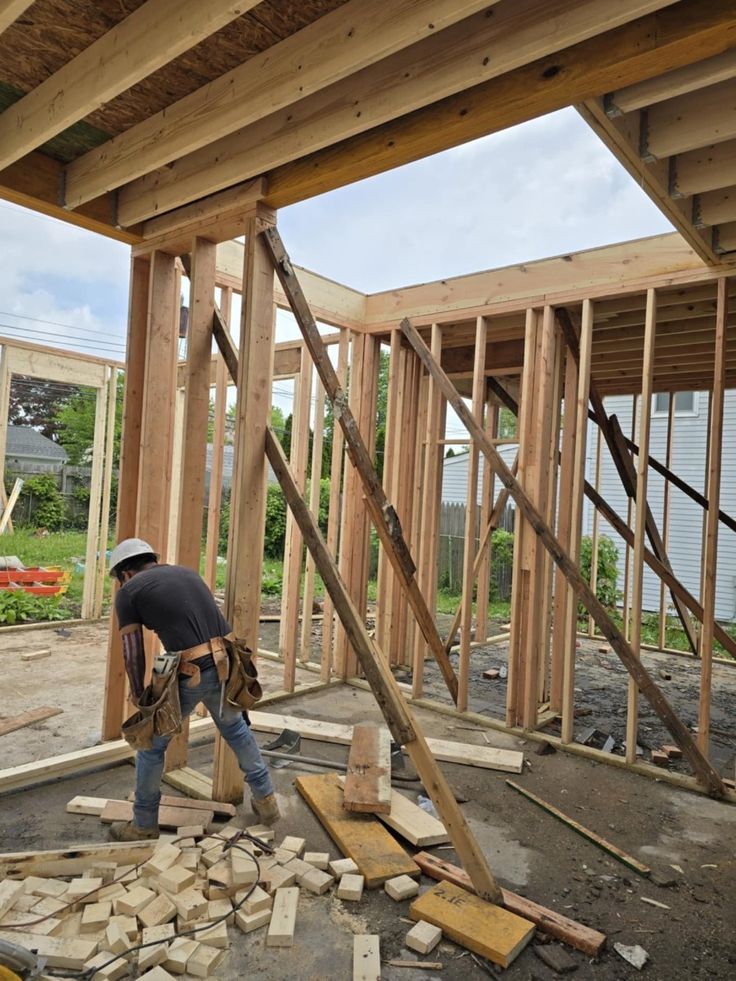 Construction worker building wooden house frame on site.