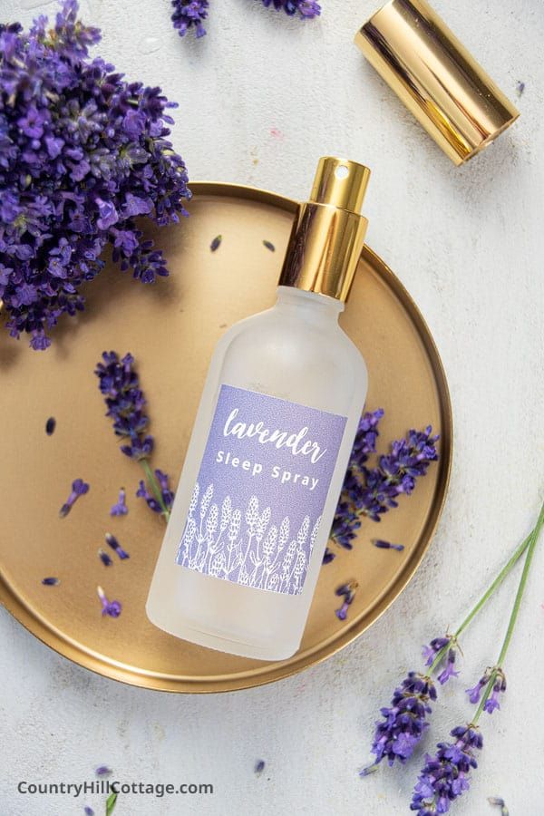 Lavender sleep spray bottle on a gold tray with fresh lavender flowers, promoting relaxation and better sleep.