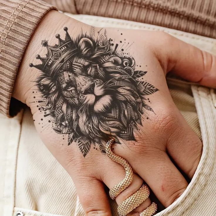 Lion tattoo with crown on hand, detailed design with serpent ring, showcasing intricate artistry and style.