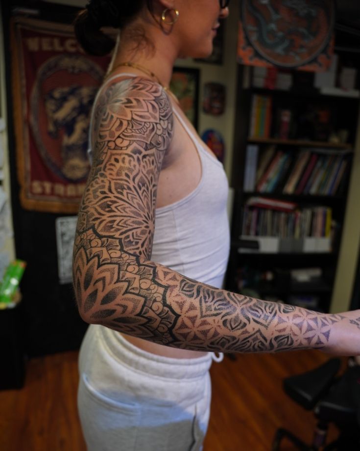 A person showcasing an intricate full-sleeve tattoo design in a tattoo studio setting.