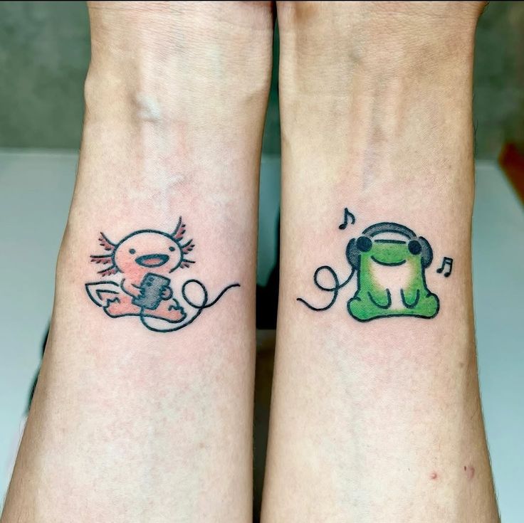 Cute axolotl and frog tattoos on wrists, connected by headphones, sharing music together.