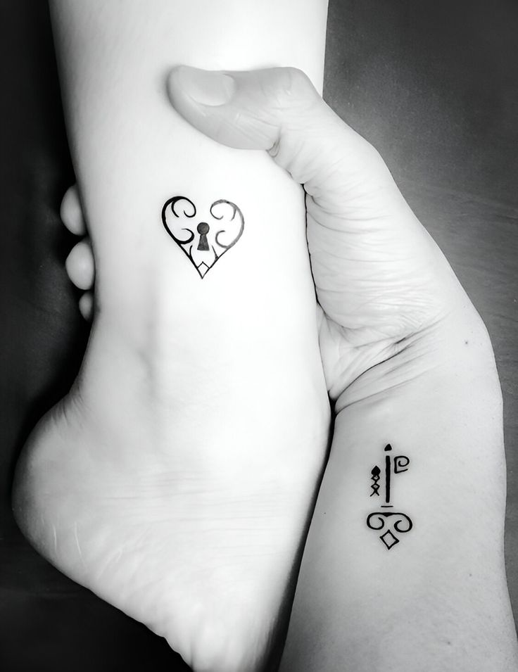 Matching key and heart lock tattoos on wrist and ankle in black ink.