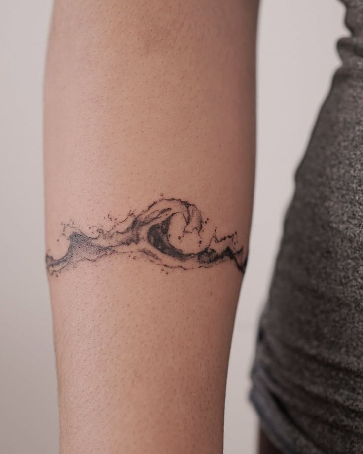 Minimalist wave tattoo on forearm, symbolizing nature and fluidity.