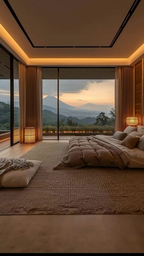 Modern bedroom with panoramic mountain view, large windows, cozy decor, and warm lighting at sunset.