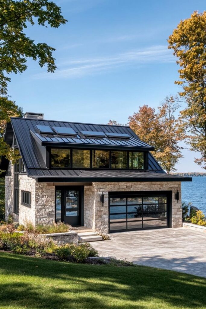 Modern lakefront house with stone facade, black metal roof, and large windows overlooking the water.