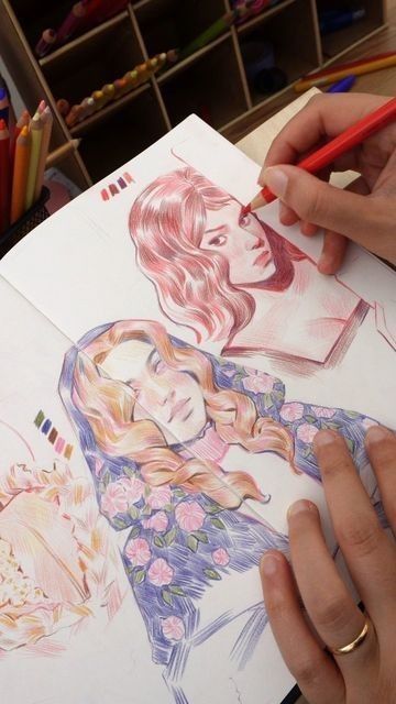 Artist drawing detailed portraits with colored pencils in a sketchbook.