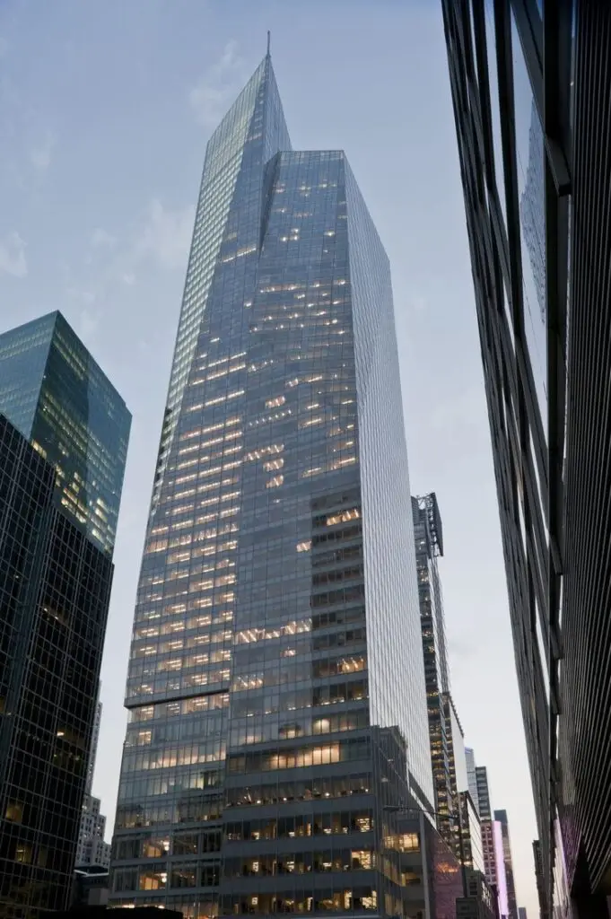 Tall modern skyscraper with glass facade in cityscape, captured at dusk.