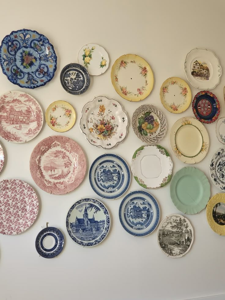 Wall display of colorful, vintage decorative plates with floral and scenic patterns for home decor inspiration.