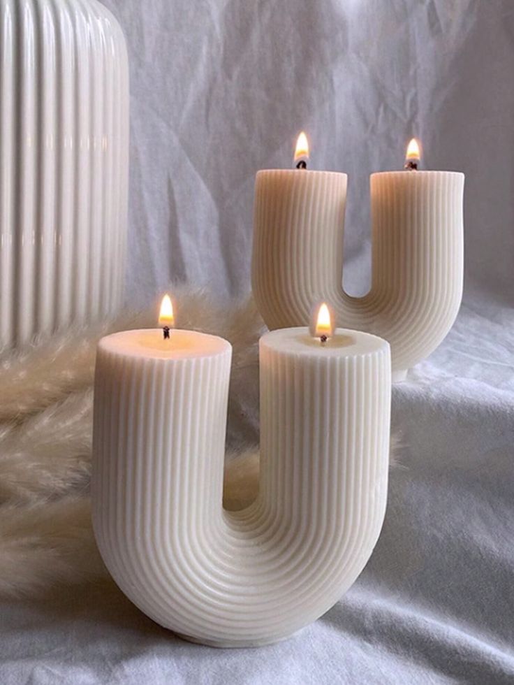 Stylish U-shaped candles with soft glow on a textured surface, adding a cozy and modern touch to home decor.