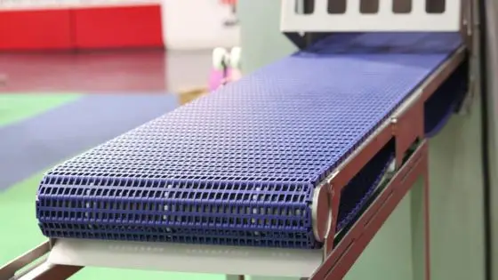 Blue industrial conveyor belt in a factory setting, used for efficient material transport and production processing.