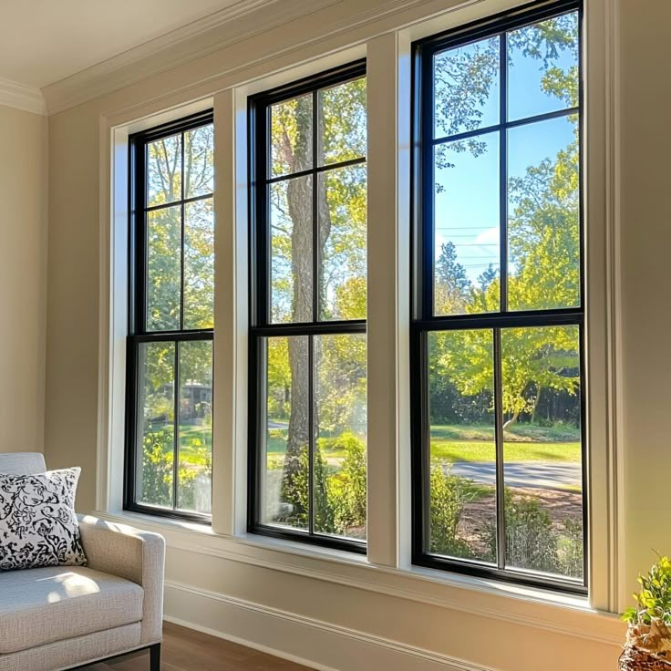 Bright living room with large windows showcasing a scenic outdoor view, framed by light walls and a cozy couch.