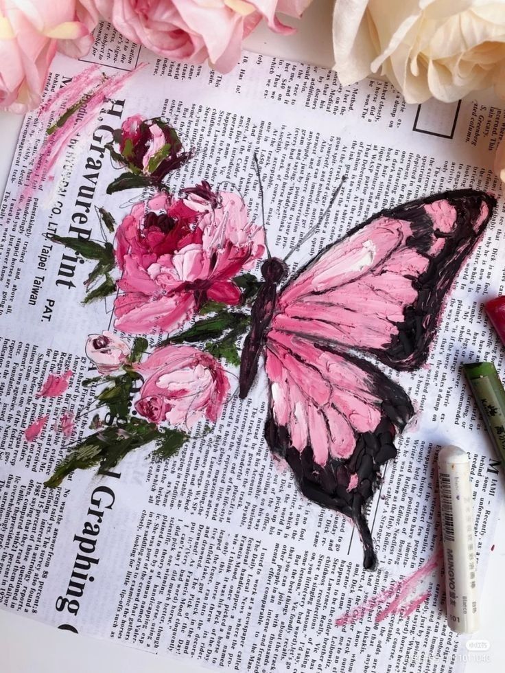 Pink butterfly and roses painted on newspaper, surrounded by pastel pencils and flowers.