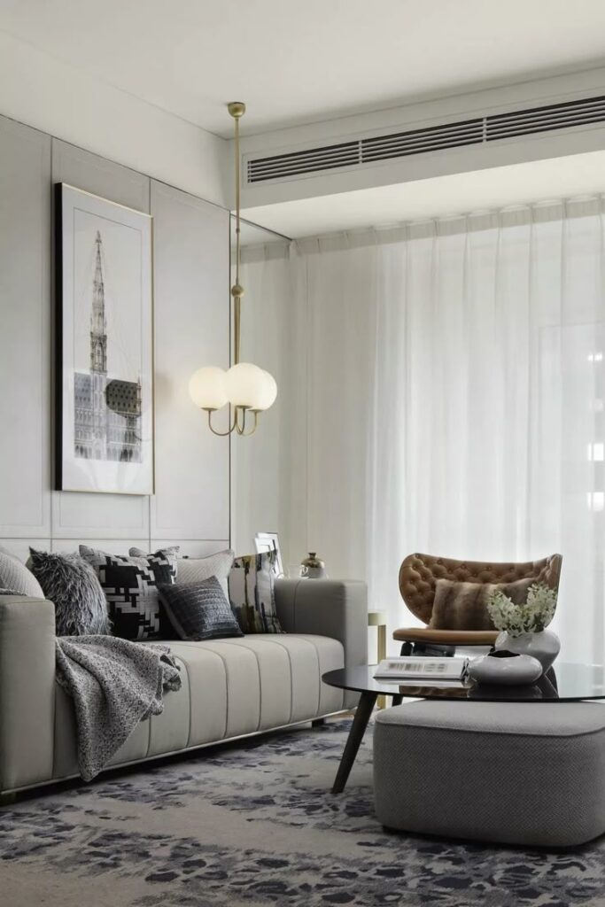 Modern living room with gray sofa, stylish armchair, and contemporary decor, featuring a pendant light and wall art.