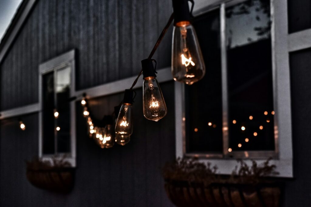 String lights hanging on a house exterior, illuminating a cozy evening ambiance.