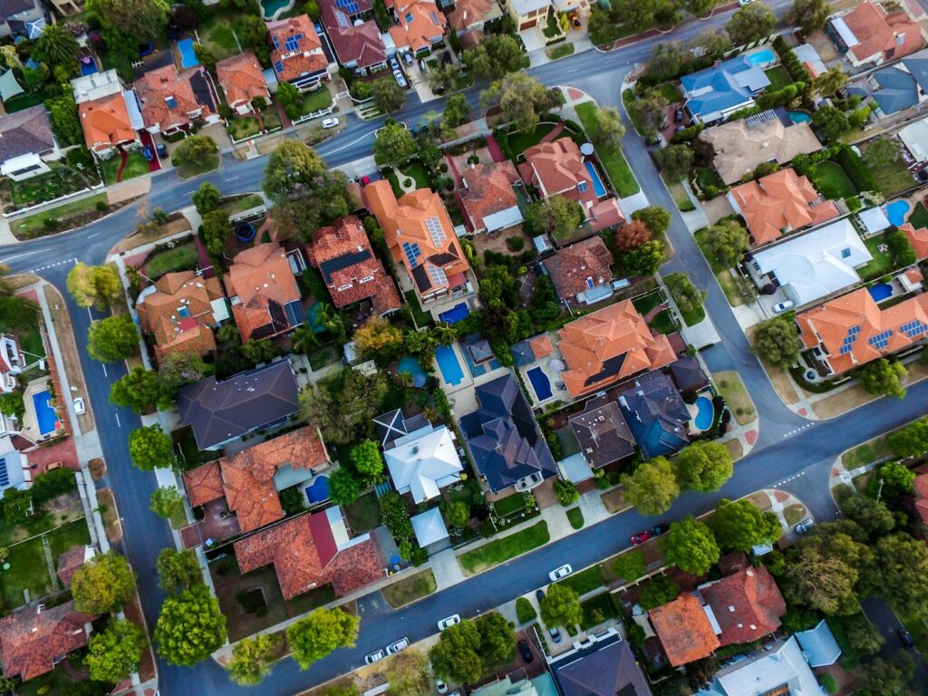 Aerial view of suburban neighborhood with organized streets and houses, lined with trees and small yards.