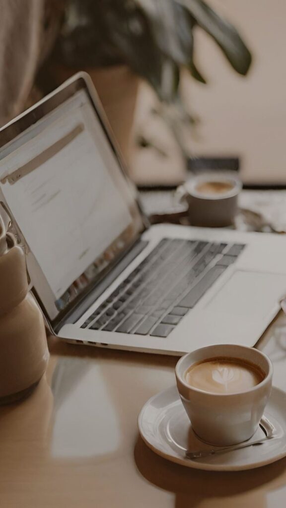 Laptop on table with latte art coffee, cozy workspace setting.